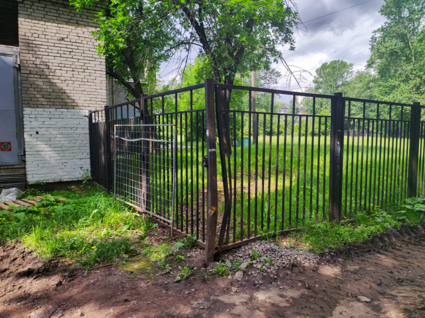 Металлические ворота и секционный забор у кирпичного технического здания