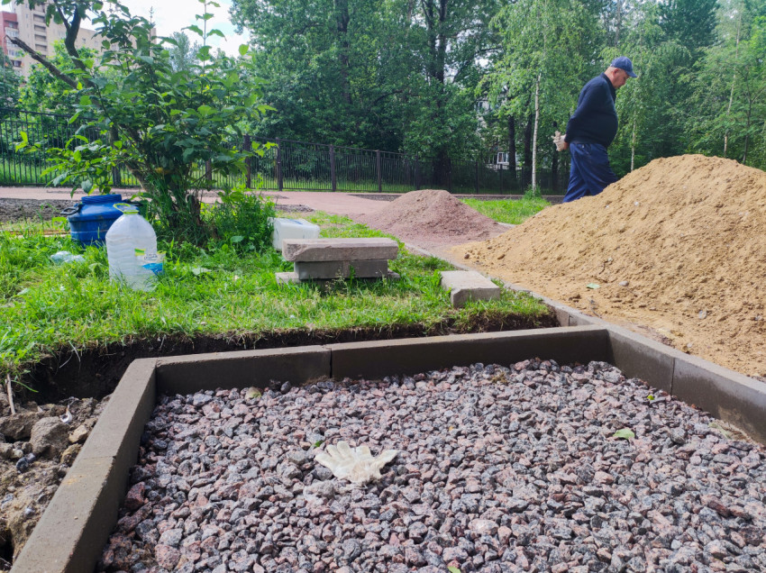 Щебёночная подушка в бордюрной рамке и строительные материалы на участке благоустройства