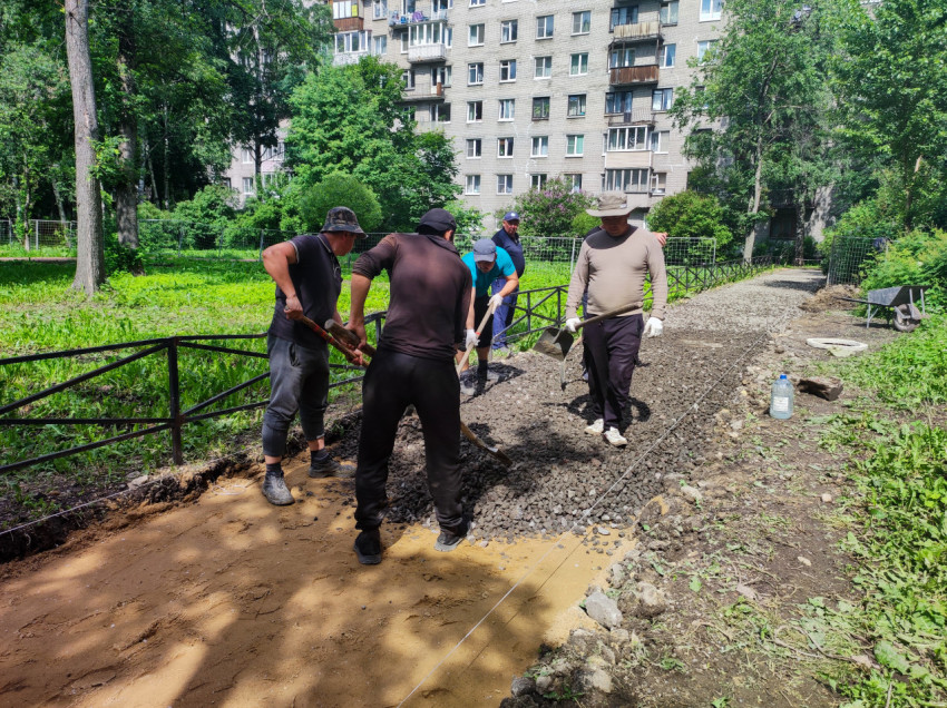 Рабочие выравнивают щебень по разметочным шнурам на ремонтируемой дворовой дорожке