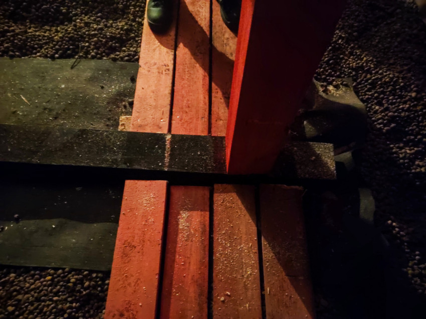 Верхний ракурс на узел деревянных подпорок и настила с рабочими ботинками на строительной площадке