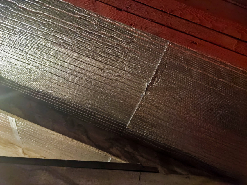 Фольгированная теплоизоляция под кровлей со швом и крепежом, крупный план