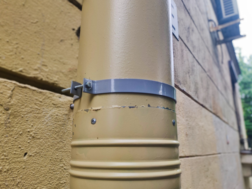 Хомут крепления водосточной трубы на фасаде крупным планом