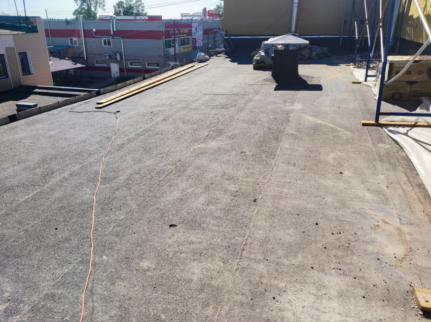 Плоская кровля с рулонным покрытием, досками и кабелем на стройплощадке