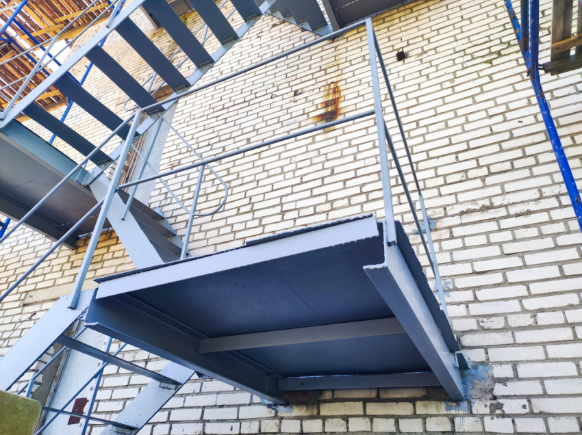 Металлическая пожарная лестница и площадка на кирпичном фасаде крупным планом