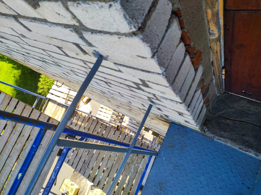 Металлическая площадка и лестница строительных лесов у кирпичной стены