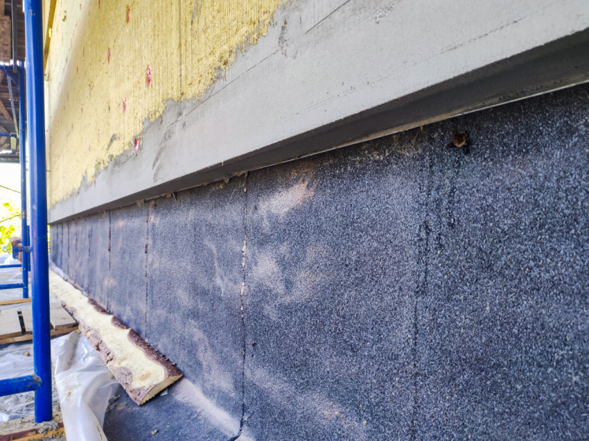 Узел цоколя с гидроизоляцией и утеплением фасада под армирующий слой рядом со строительными лесами