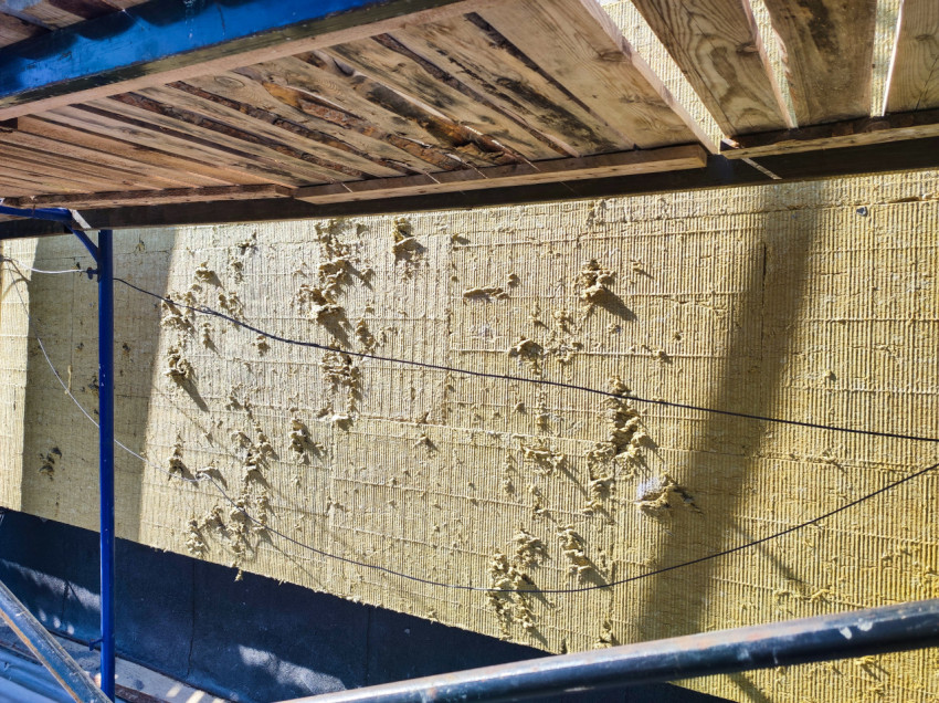 Минераловатные плиты на фасаде с клеевыми маяками и протянутыми кабелями под настилом лесов