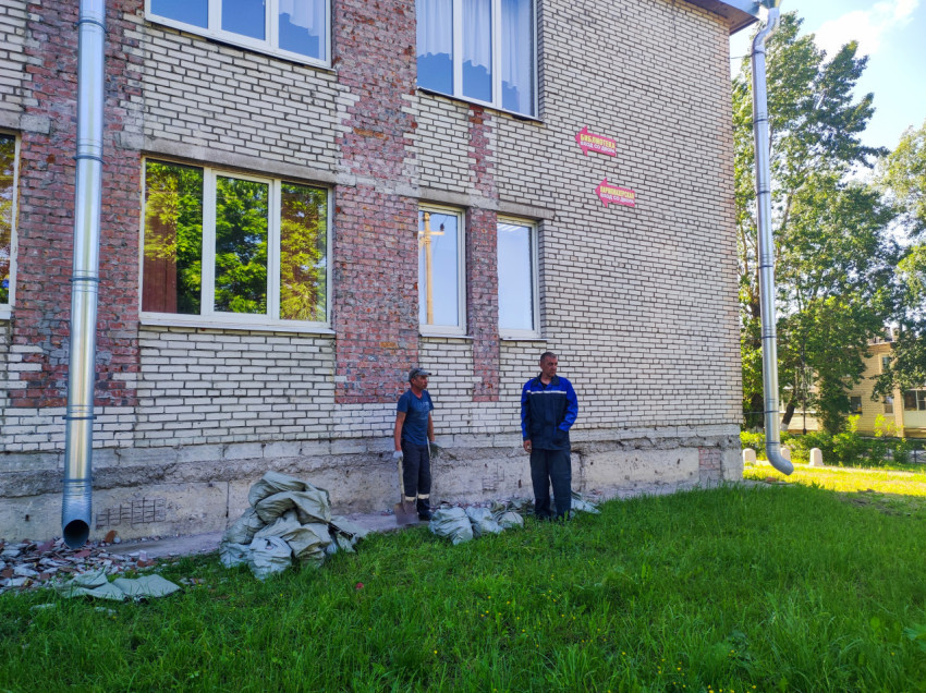 Фасад кирпичного здания с указателями «Библиотека» и «Парикмахерская» во время ремонта