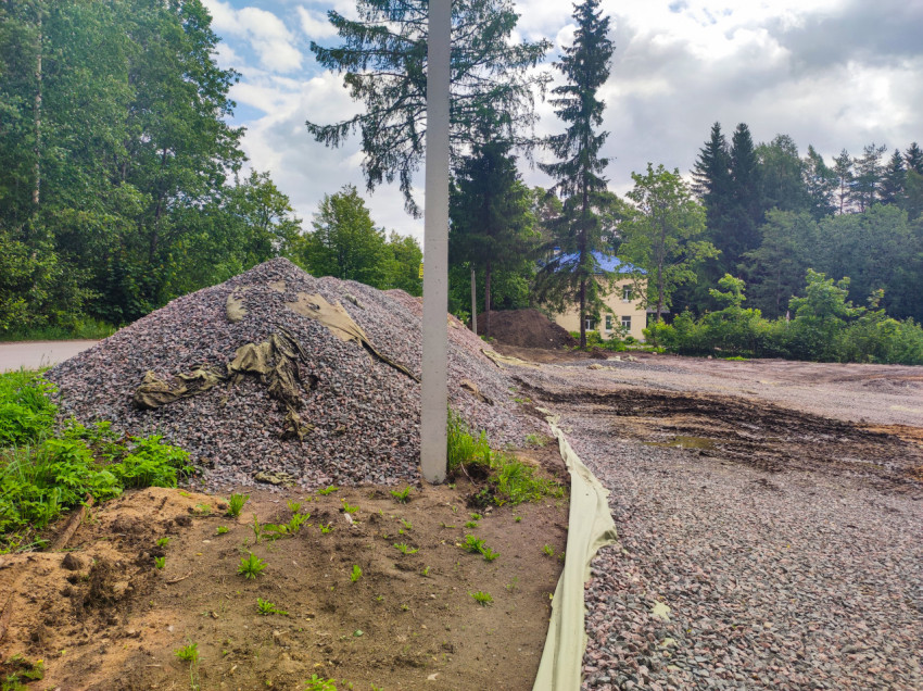 Кучи щебня и подготовка основания на строительной площадке у леса