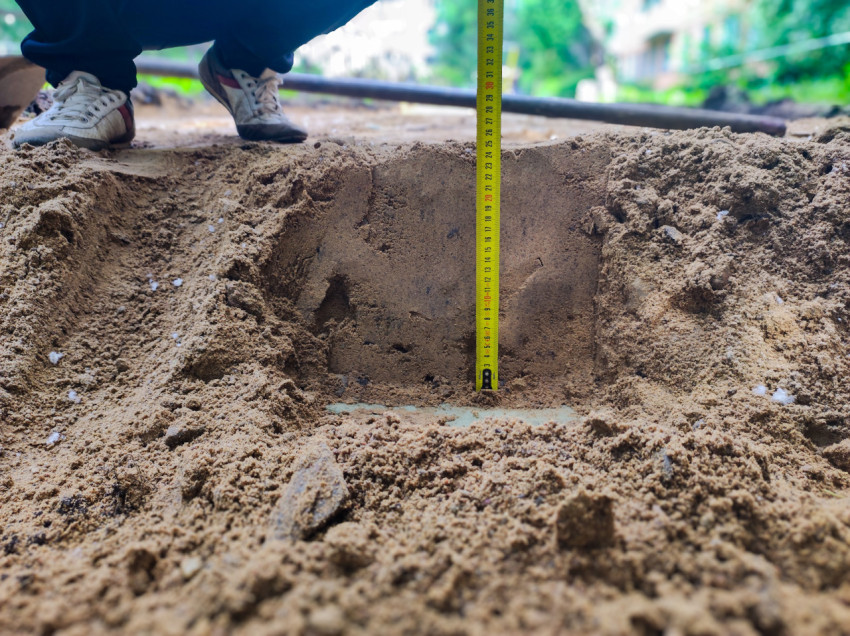 Крупный план измерения глубины песчаной выемки рулеткой на стройплощадке