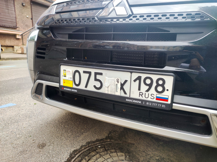 Номерной знак и решётка радиатора Mitsubishi крупным планом, номер частично закрыт