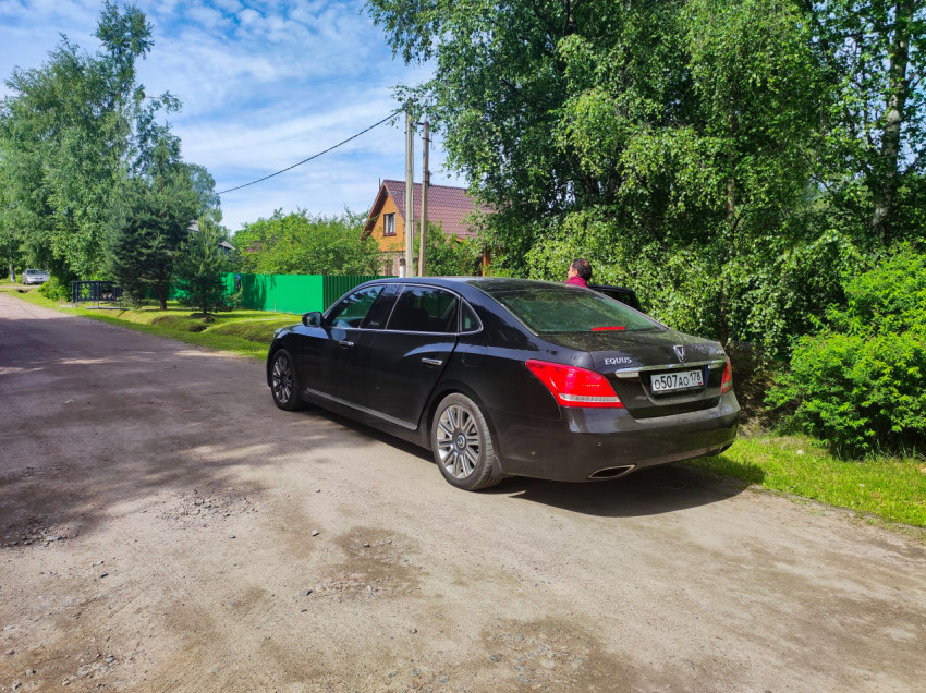 Черный седан Hyundai Equus и человек у обочины на грунтовой дороге