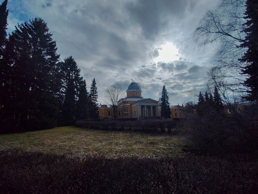 Главное здание обсерватории среди деревьев под пасмурным небом