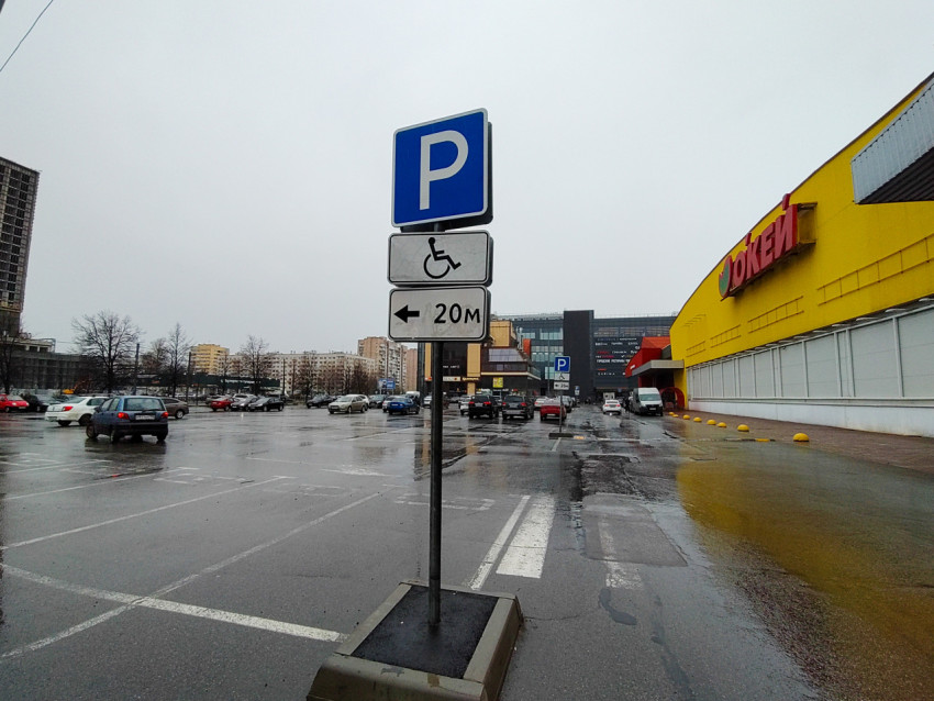 Парковочная стойка с указателем для маломобильных водителей рядом с торговым центром