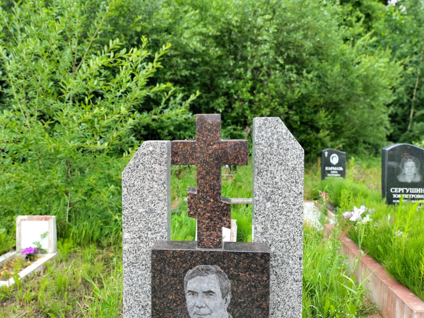Надгробия с гранитными крестами и портретом на кладбищенском участке