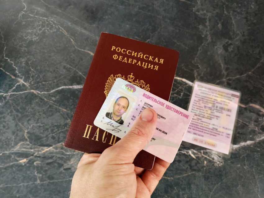 Паспорт и водительское удостоверение в руке на мраморной поверхности