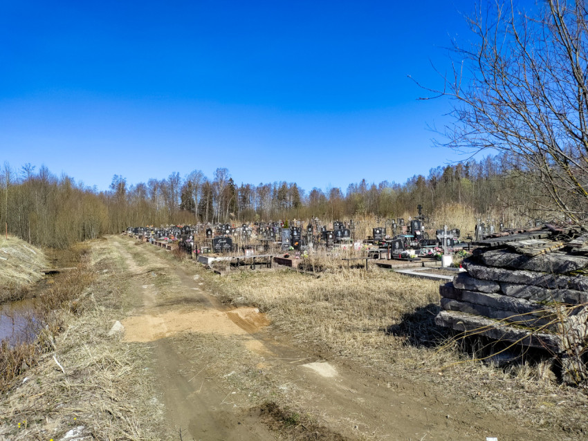 Загородное кладбище с грунтовой дорогой на фоне весеннего пейзажа