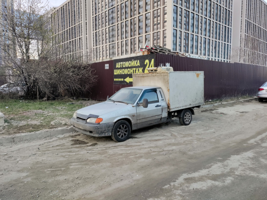 Грузовой автомобиль с грязным кузовом на фоне высотного жилого комплекса