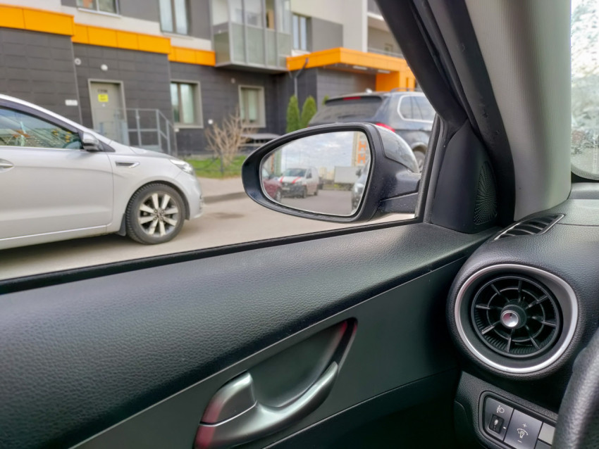 Вид из салона автомобиля на левое боковое зеркало и припаркованные машины