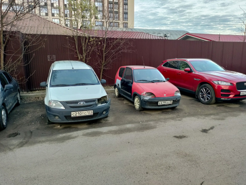 Старые автомобили припаркованы во дворе на фоне многоэтажек