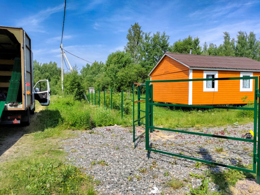 Металлические ворота и грузовик на фоне загородного дома