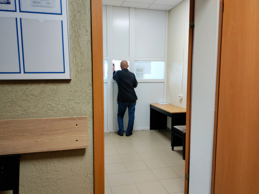 Мужчина у окна приёма в административном помещении
