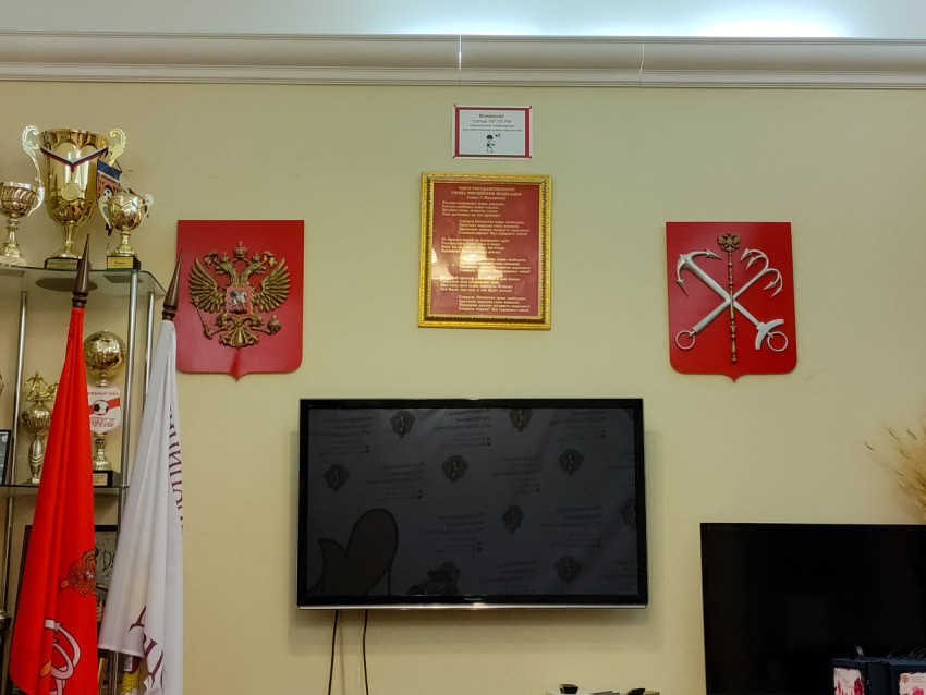 Стена с гербами РФ и Санкт-Петербурга над экраном