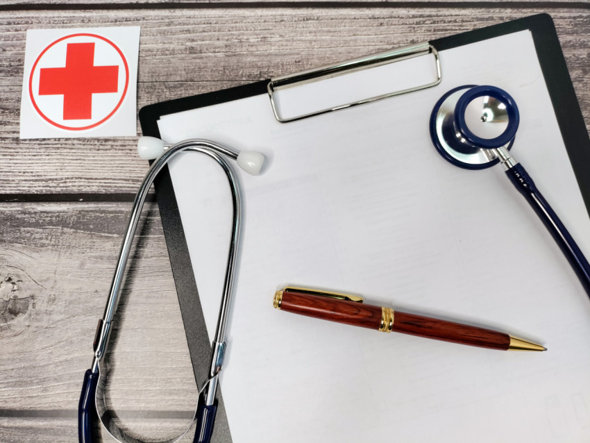 Медицинский стетоскоп и ручка на бланке с символом помощи