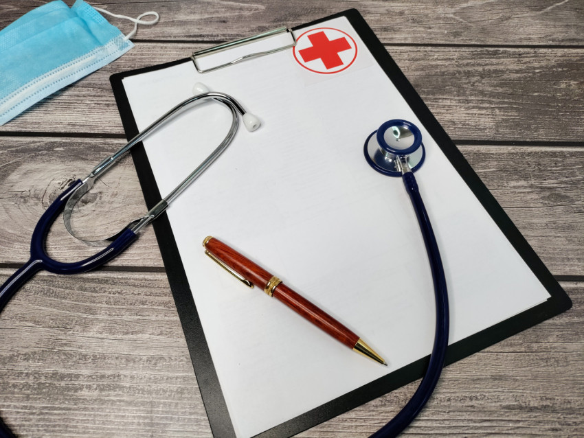 Медицинский стетоскоп, маска и бланк на деревянном столе