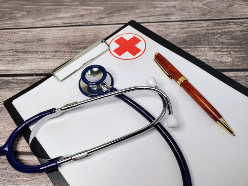 Стетоскоп и ручка на медицинском бланке с символом Красного Креста