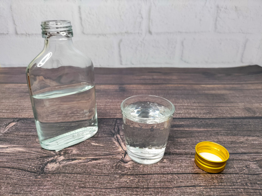 Открытая бутылка и налитая рюмка на деревянной поверхности