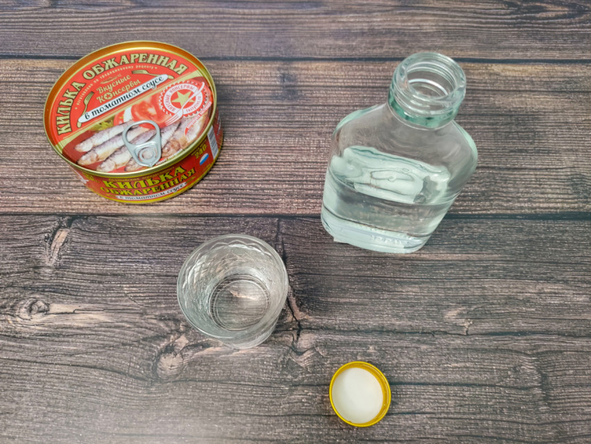 Вид сверху на водку, рюмку и банку кильки