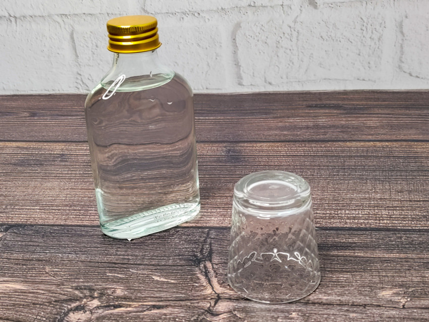 Бутылка водки и перевёрнутая стопка на деревянном столе