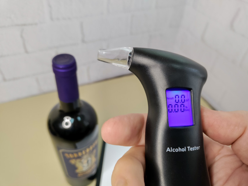 Электронный алкотестер в руке с включённым дисплеем