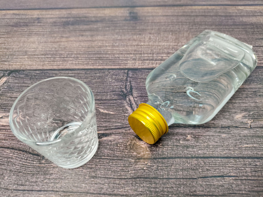 Пустая рюмка и закрытая бутылка водки на столе