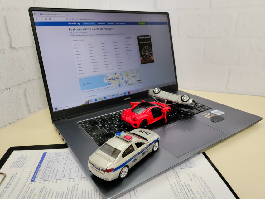 Игрушечные автомобили на ноутбуке и документы по страхованию
