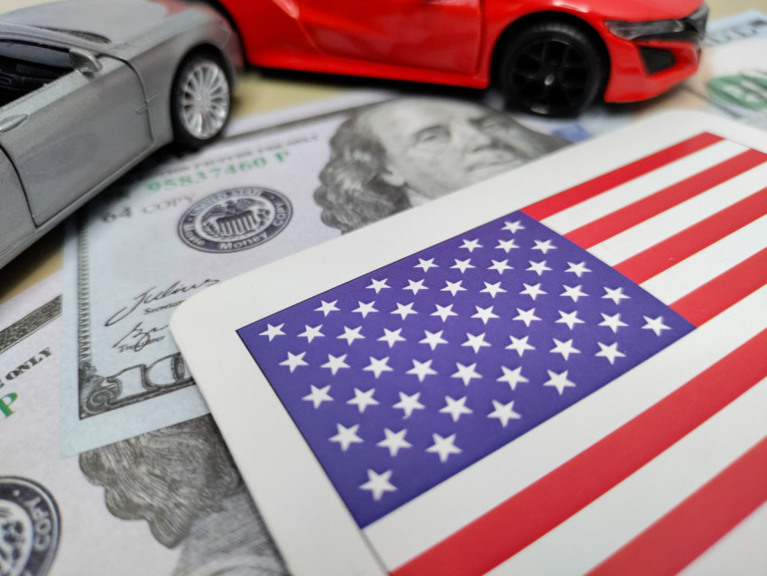 Флаг США среди банкнот и миниатюрных автомобилей