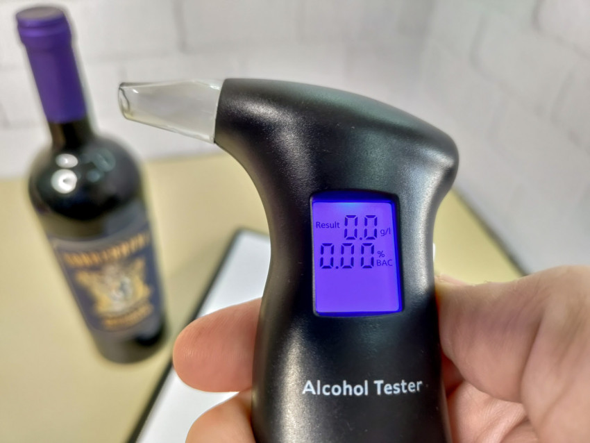 Электронный алкотестер в руке с подсветкой дисплея