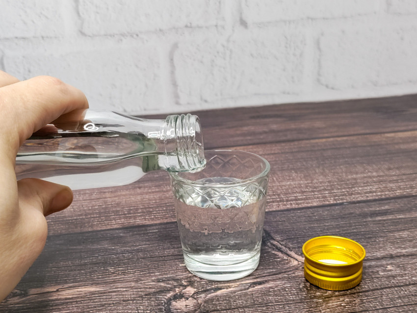 Наливание прозрачной жидкости из бутылки в стакан