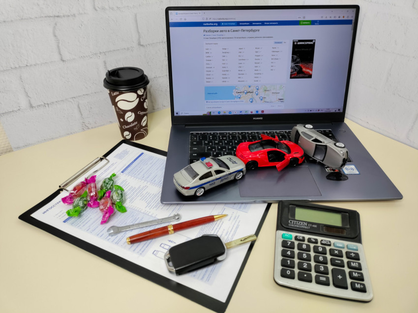 Рабочее место автоэксперта с ноутбуком и миниатюрными моделями автомобилей
