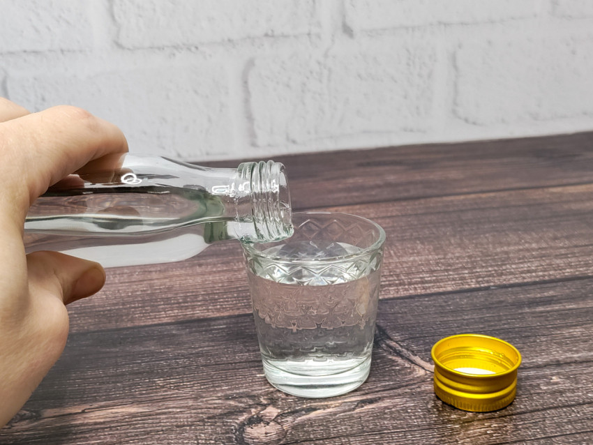 Процесс наливания прозрачного напитка в стеклянный стакан