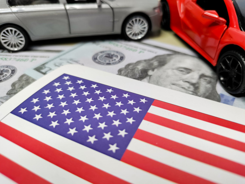Флаг США на фоне банкнот и миниатюрных автомобилей