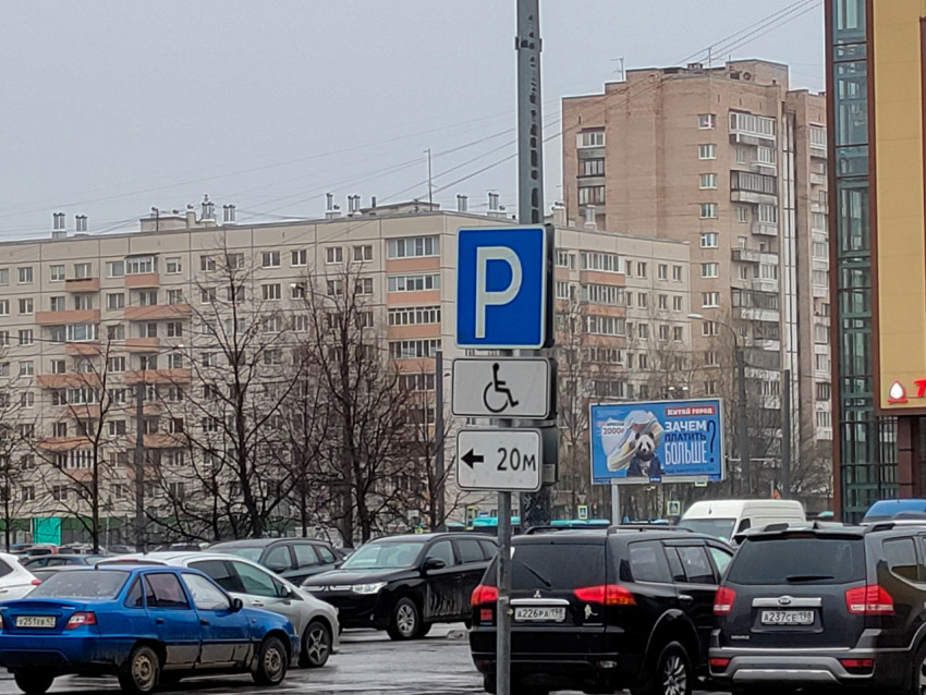 Парковочный указатель и плотный поток автомобилей на фоне жилых домов