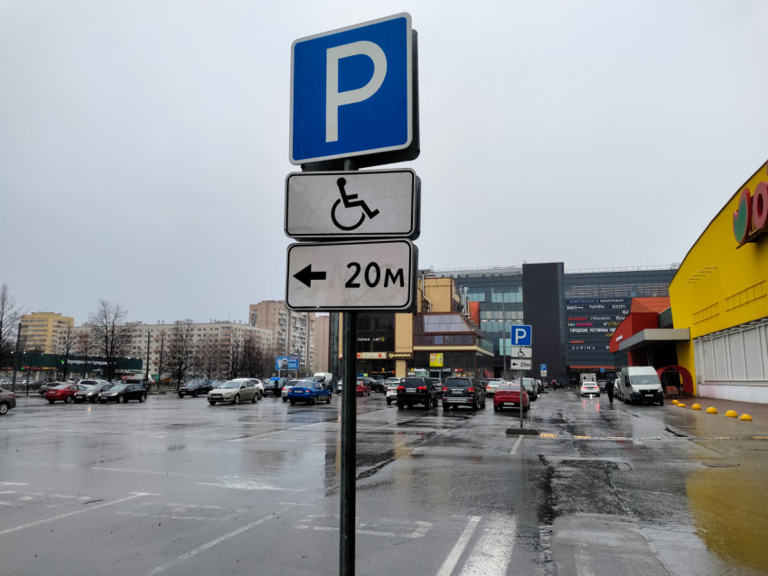 Дорожный знак парковки у крупного торгового комплекса в дождливую погоду