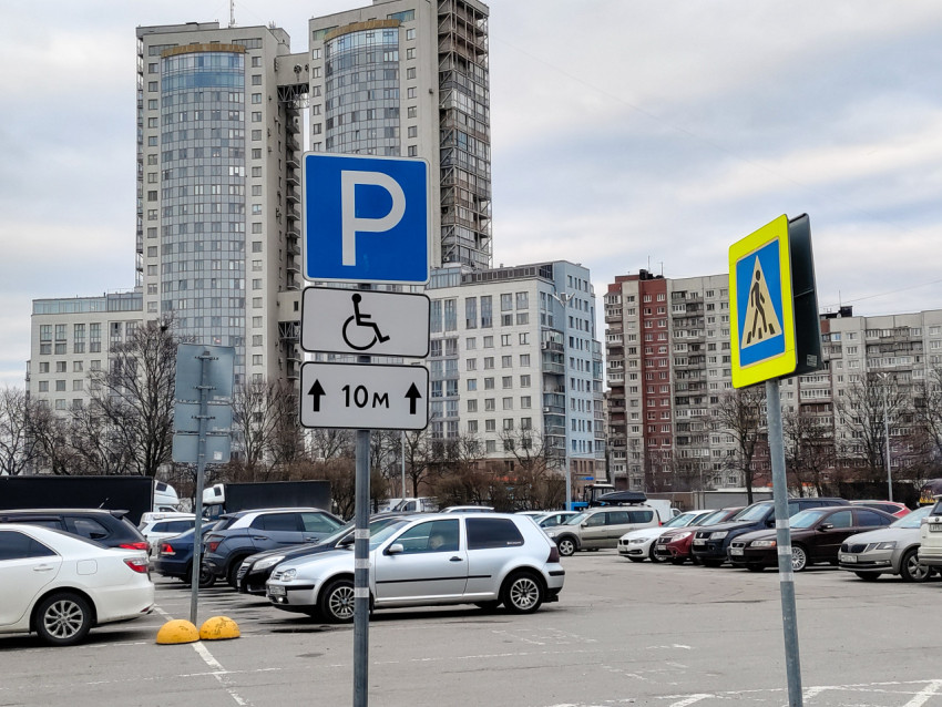 Парковочный знак и указатель для маломобильных водителей на фоне жилых высоток