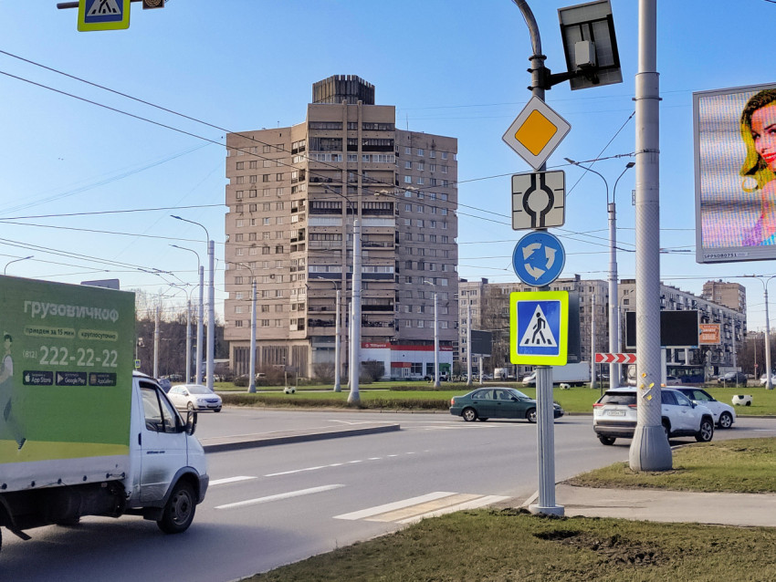 Дорожные знаки и поток автомобилей у кольцевого перекрёстка