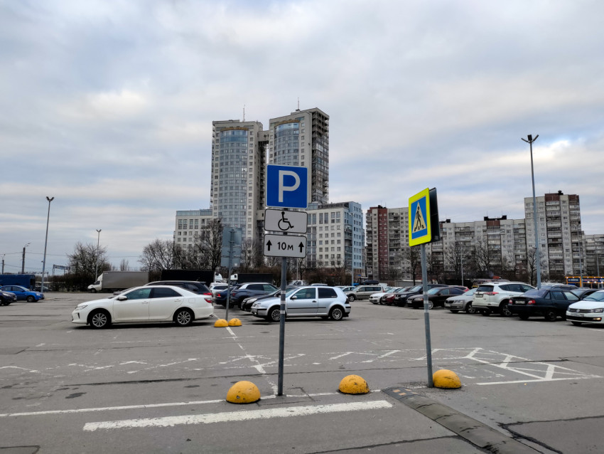 Парковочный указатель и пешеходный переход на открытой стоянке рядом с жилыми домами