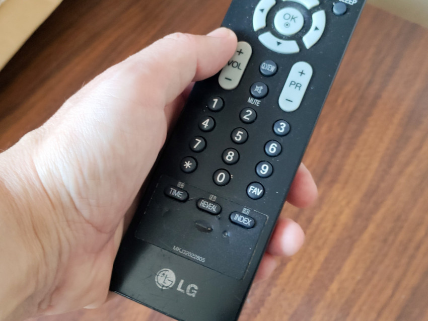 Пульт LG в руке с видимым набором цифровых кнопок