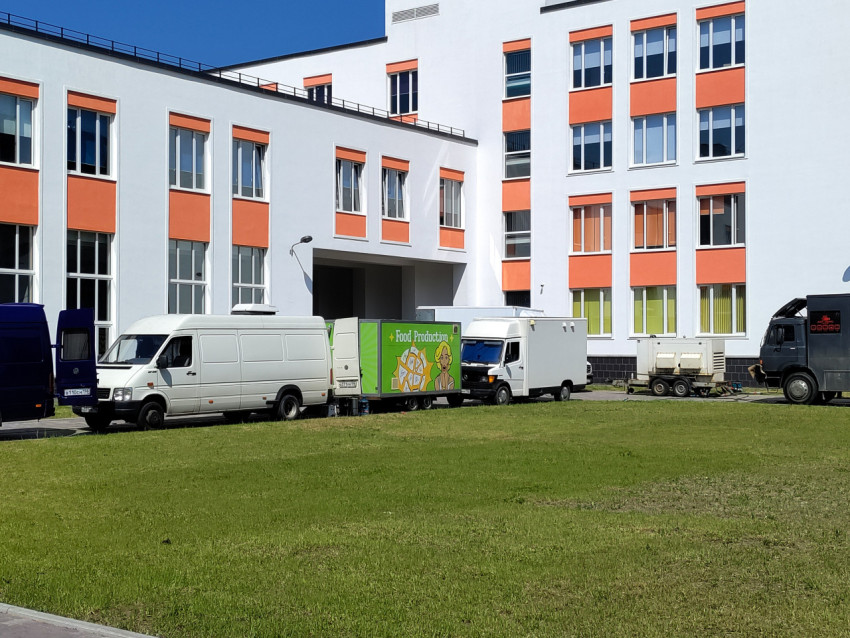 Автомобили и спецтехника у здания с бело-оранжевым фасадом