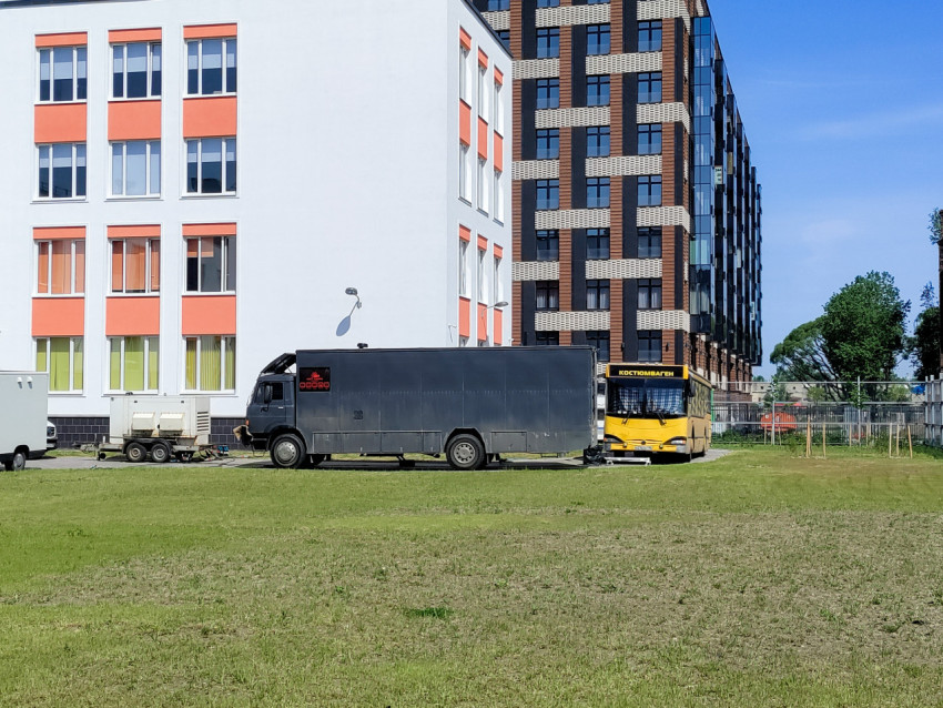 Грузовой фургон и автобус съемочной группы у здания школы